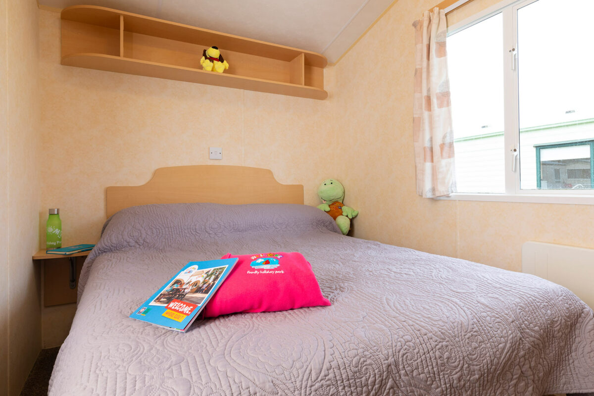 Master bedroom with jumper and brochure in the Sunrise caravan at Welcome Family Holiday Park