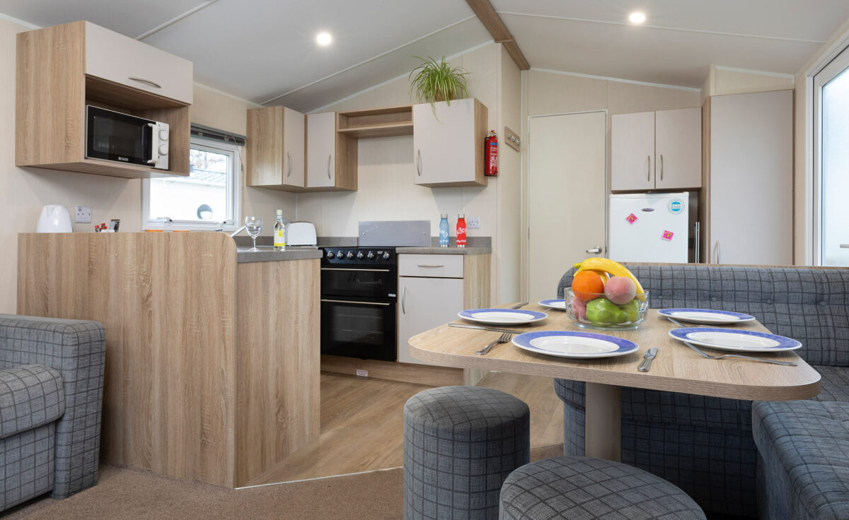 Kitchen and dining area with a colourful bowl of fruit in the CasaMor premier caravan at Welcome Family Holiday Park