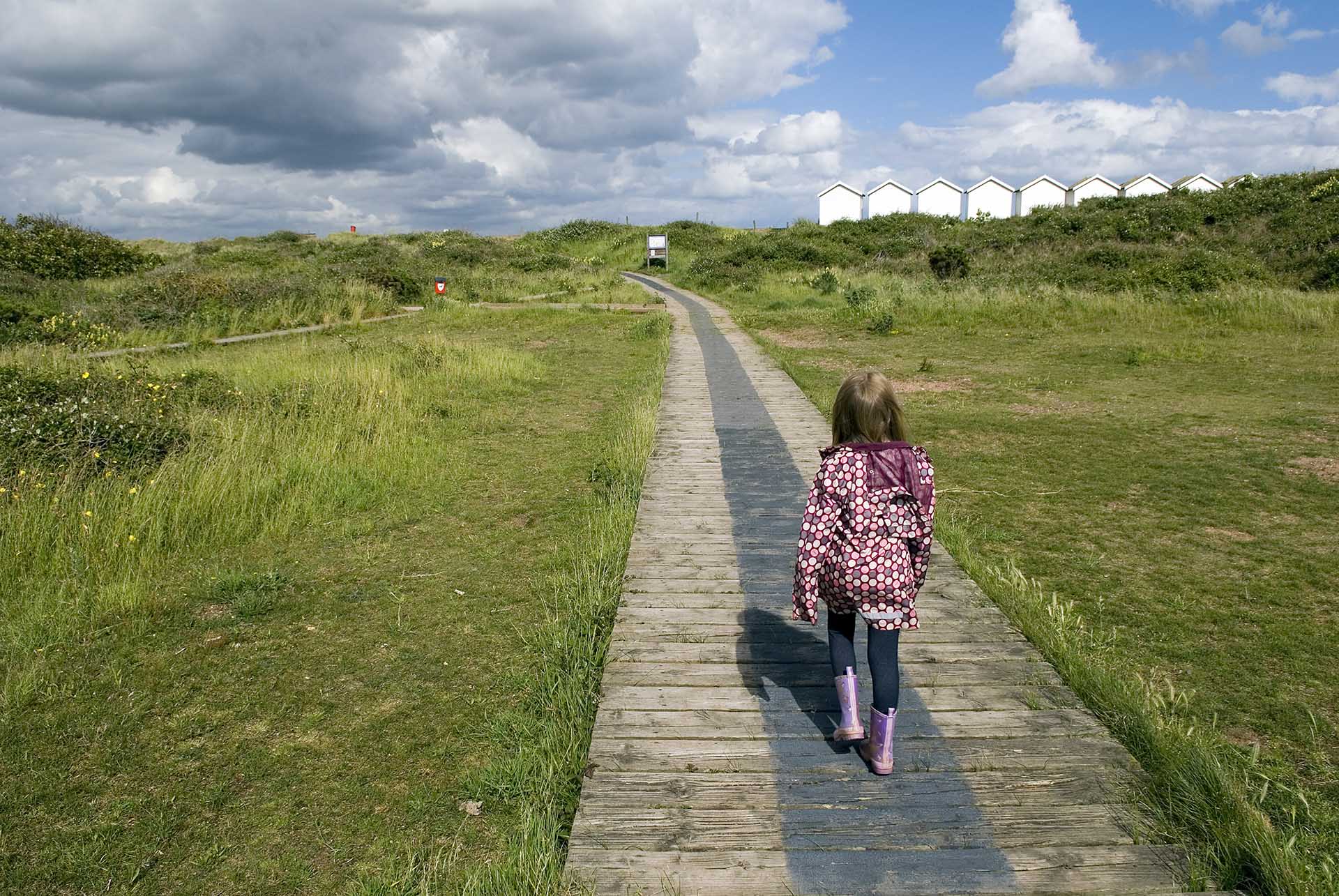 Girl walking towards beach huts at Dawlish Warren