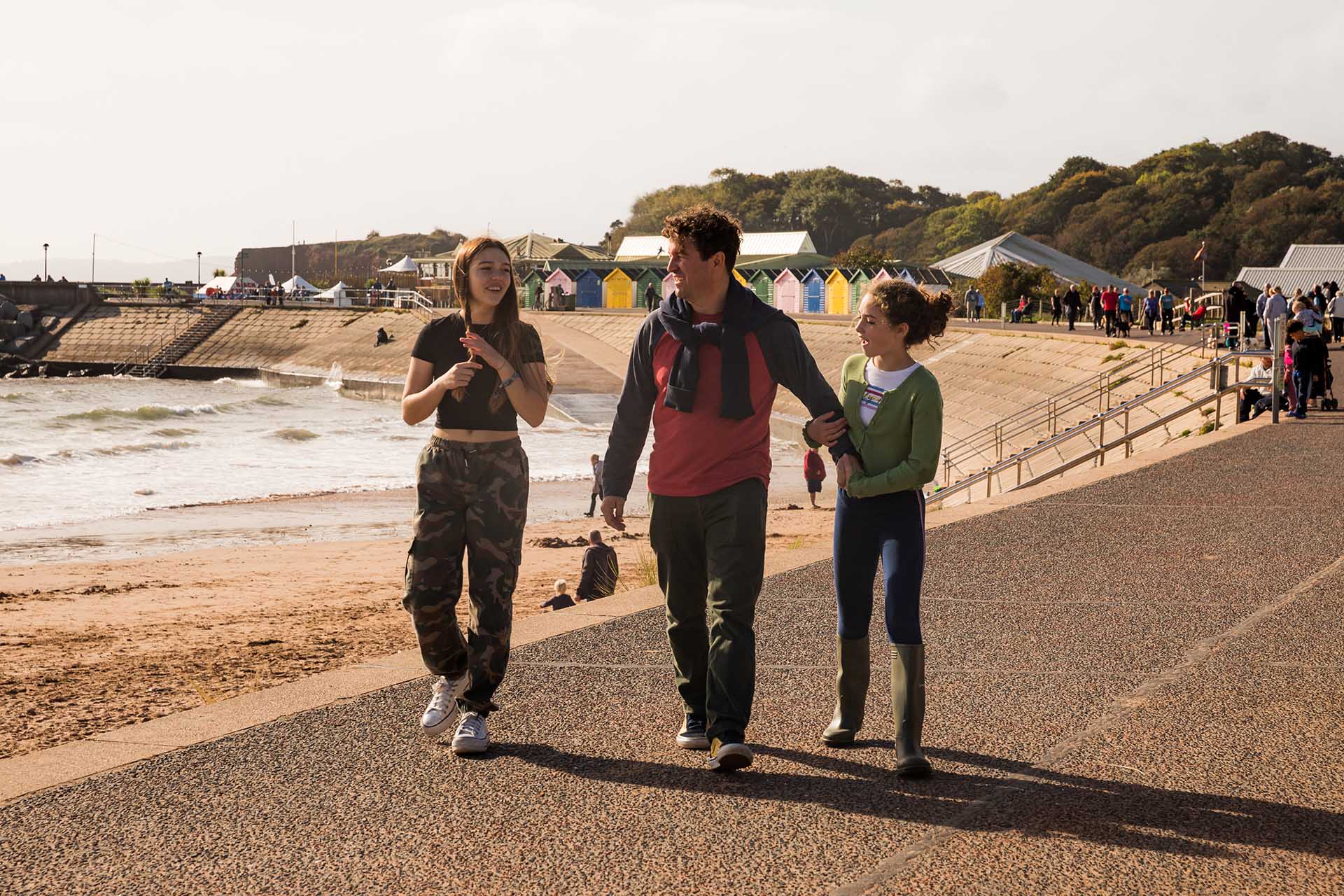 Dad and daughters walking along Dawlish Warren Beach