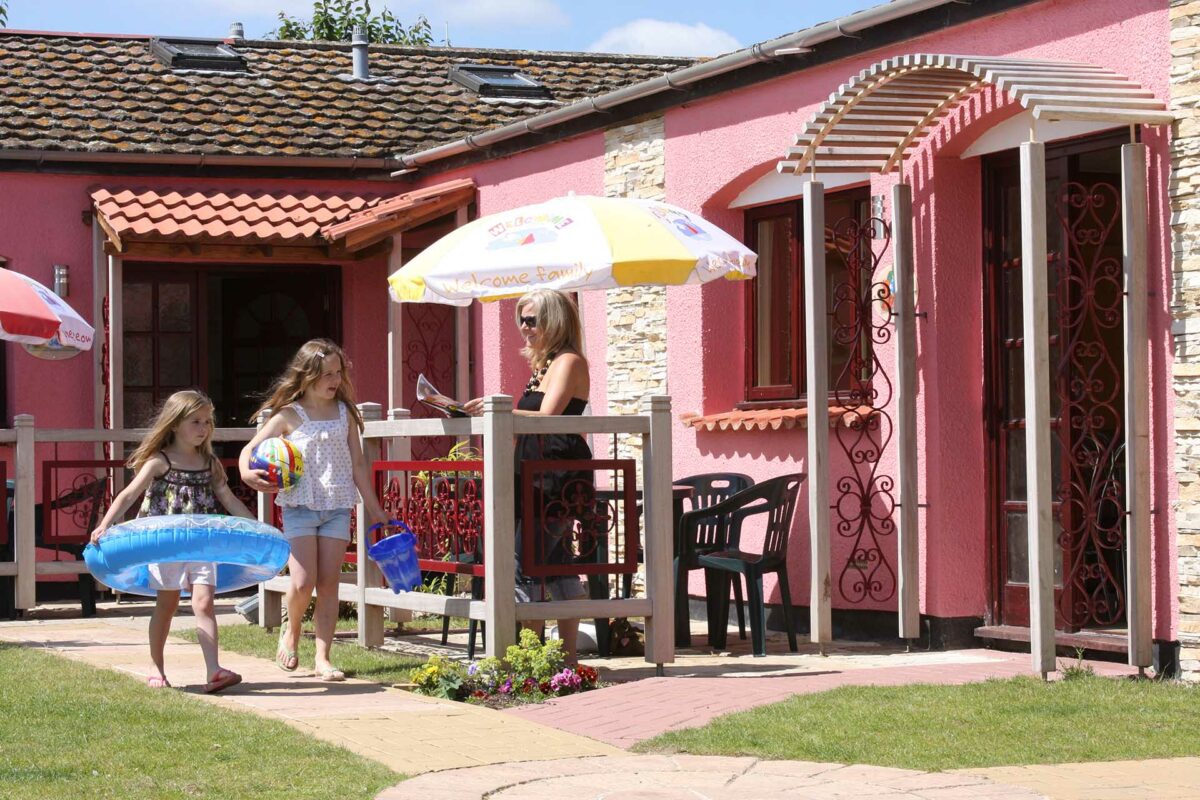 Outside Welcome Wavesurfer lodge in sunshine with kids ready for beach